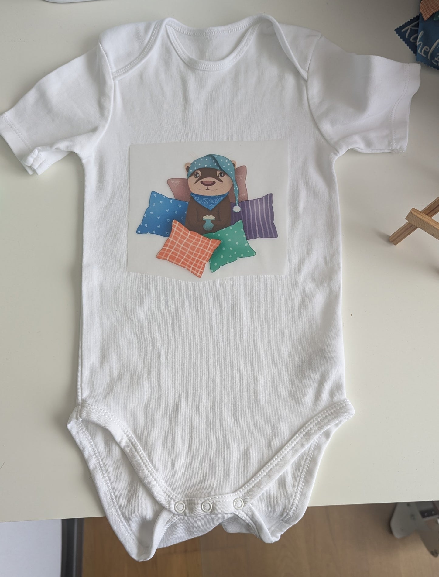 Baby-Body | "Cozy Otter - Kuschelzeit" | für Neugeborene und Kleinkinder | kleiner Otter in mitten von Kissen mit heißer Schokolade in den Pfoten